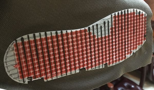 Close-up of a textured shoe sole with red and white patterns.